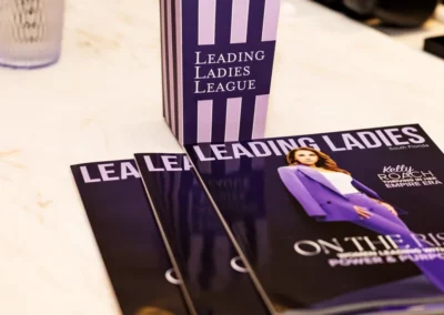 Stack of three glossy magazines below a purple striped box of popcorn, all placed on a table.