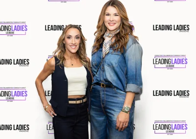 Two women smiling in front of "Leading Ladies League" backdrop.